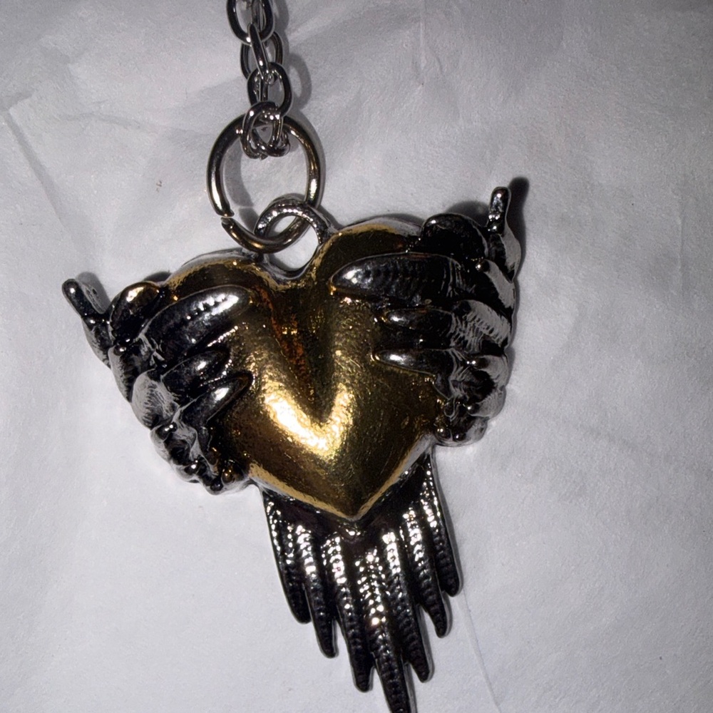 Angel wing wrapped around a gold heart. Silver and Gold Heart Pendant Necklace